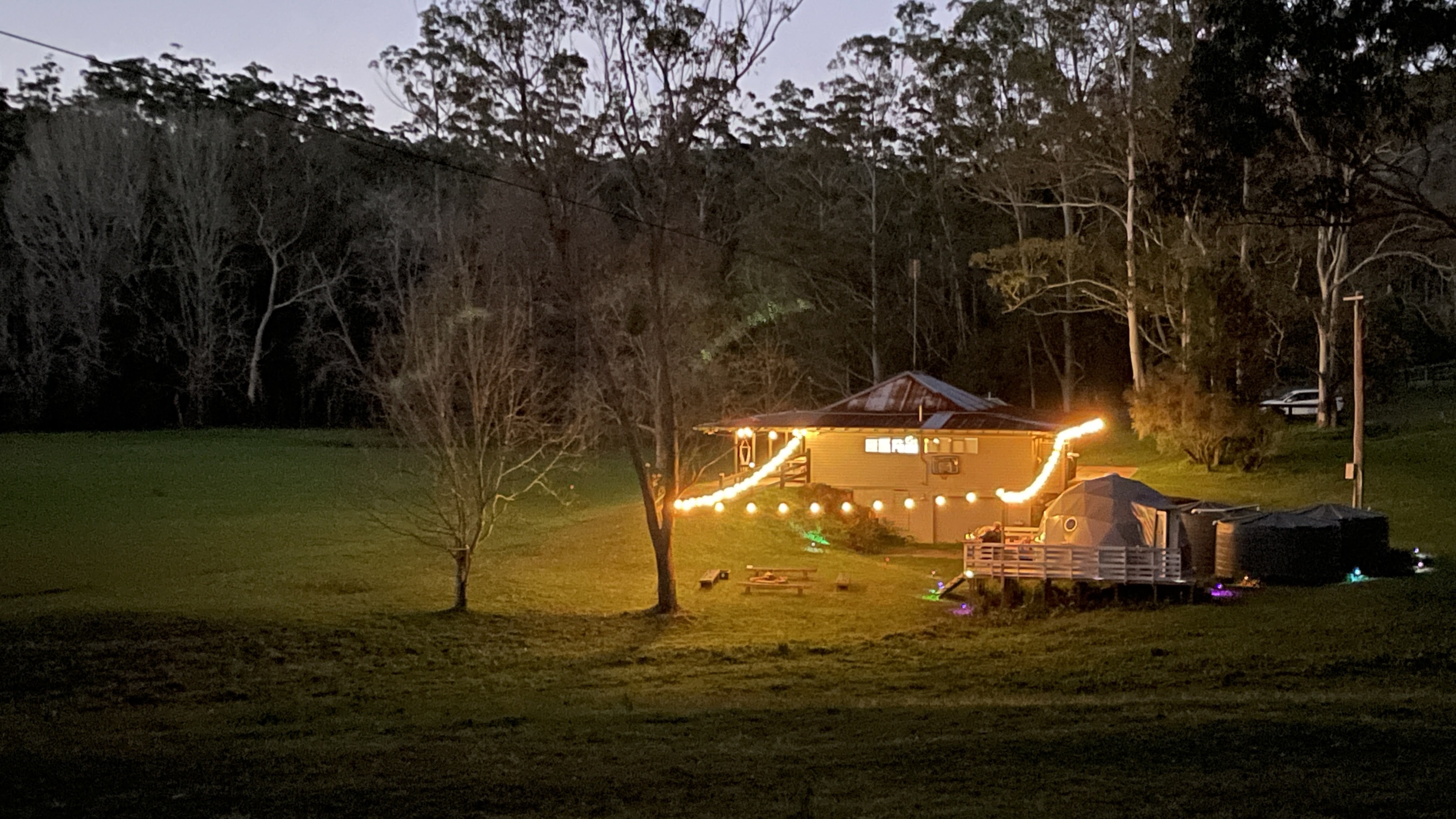 The Burrow and clubhouse lit by festoon lights at dusk