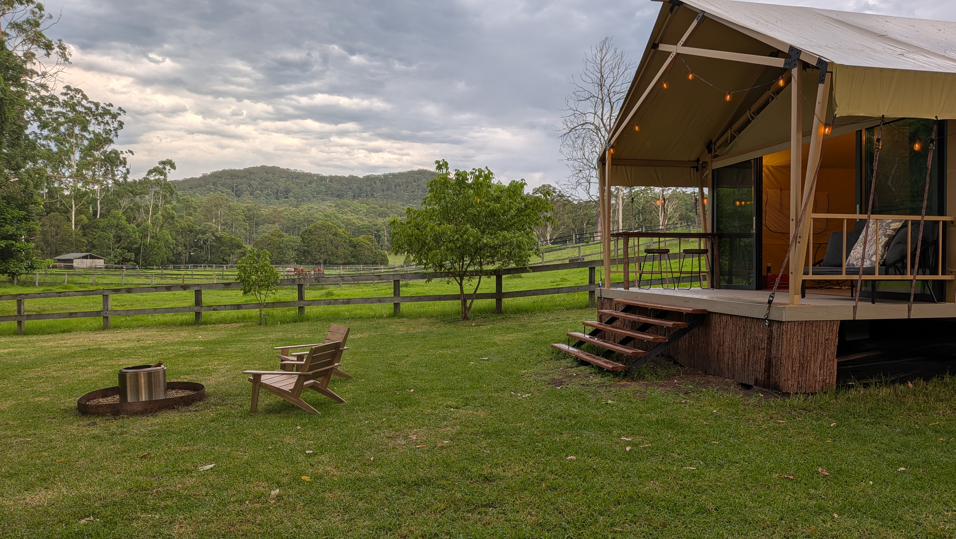 Landscape view — fire pit, deck entry with bar seating, daybed, and floor-to-ceiling sliding glass doors